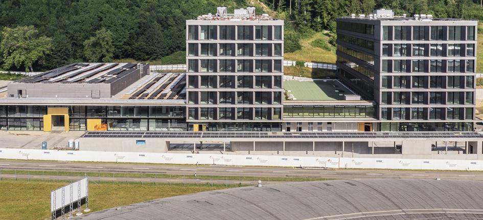 Il centro di trasferimento tecnologico Swiss PIC si sta trasferendo nel Park Innovaare e quindi nelle immediate vicinanze del PSI: il tetto rotondo in primo piano della foto appartiene alla Synchrotron Light Source  SLS, che si trova nel sito del PSI West; dietro di esso, si può vedere parte del complesso di edifici del Park Innovaare. 