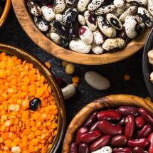 Legumes, lentils, chikpea and beans assortment in different bowls on black stone table