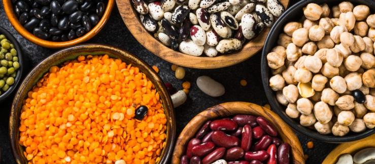 Legumes, lentils, chikpea and beans assortment in different bowls on black stone table