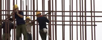 Asiatische Arbeiter bauen ein neues Gebäude.