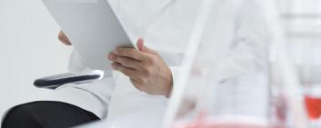 A man in a lab coat holds an iPad
