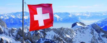 Swiss flag in front of mountain chain
