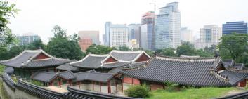 Visa su case coreane tradizionali con edifici a torre sullo sfondo.