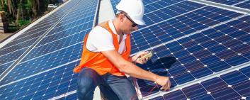 Junger Techniker überprüft Solarpanels auf einem Fabrikdach